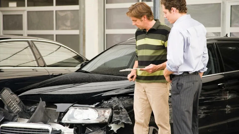 Insurance adjuster assessing damage to car --- Image by © Juice Images/Corbis