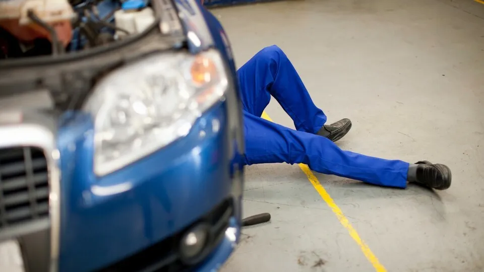 Car mechanic at work in service bay --- Image by © Zero Creatives/Corbis