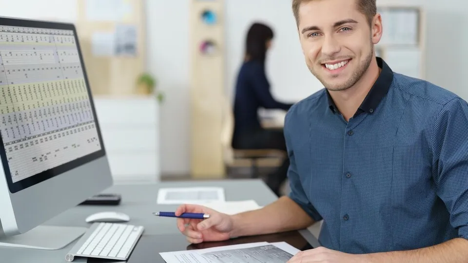 lächelnder mitarbeiter im büro arbeitet am pc