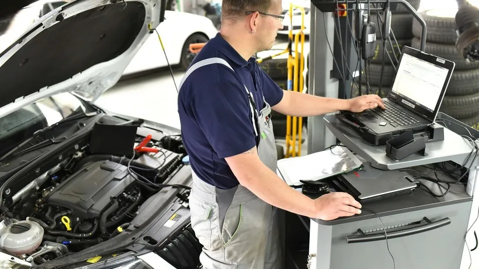 Handwerker führt Software-Update bei einem Pkw durch.