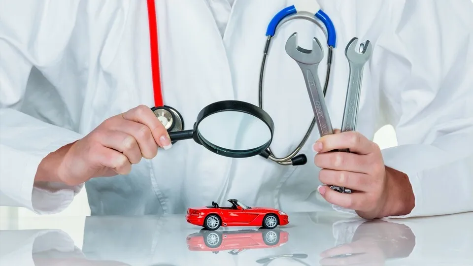 Ein Modell eines Autos wird von einem Arzt untersucht. Symbolfoto für Werkstatt, Service und Autokauf.