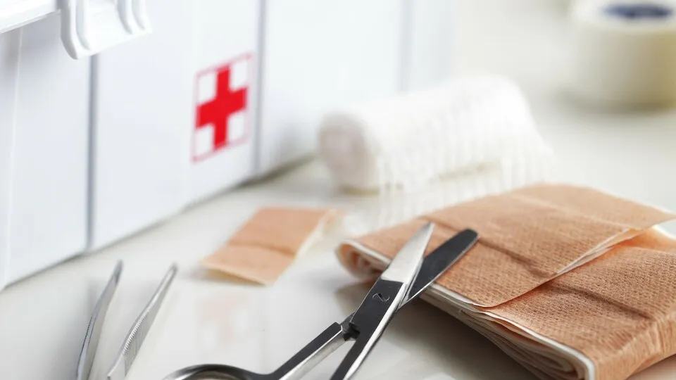 Erste Hilfe Set mit Pflastern und Schere
First aid kit with bandage and scissors on white table