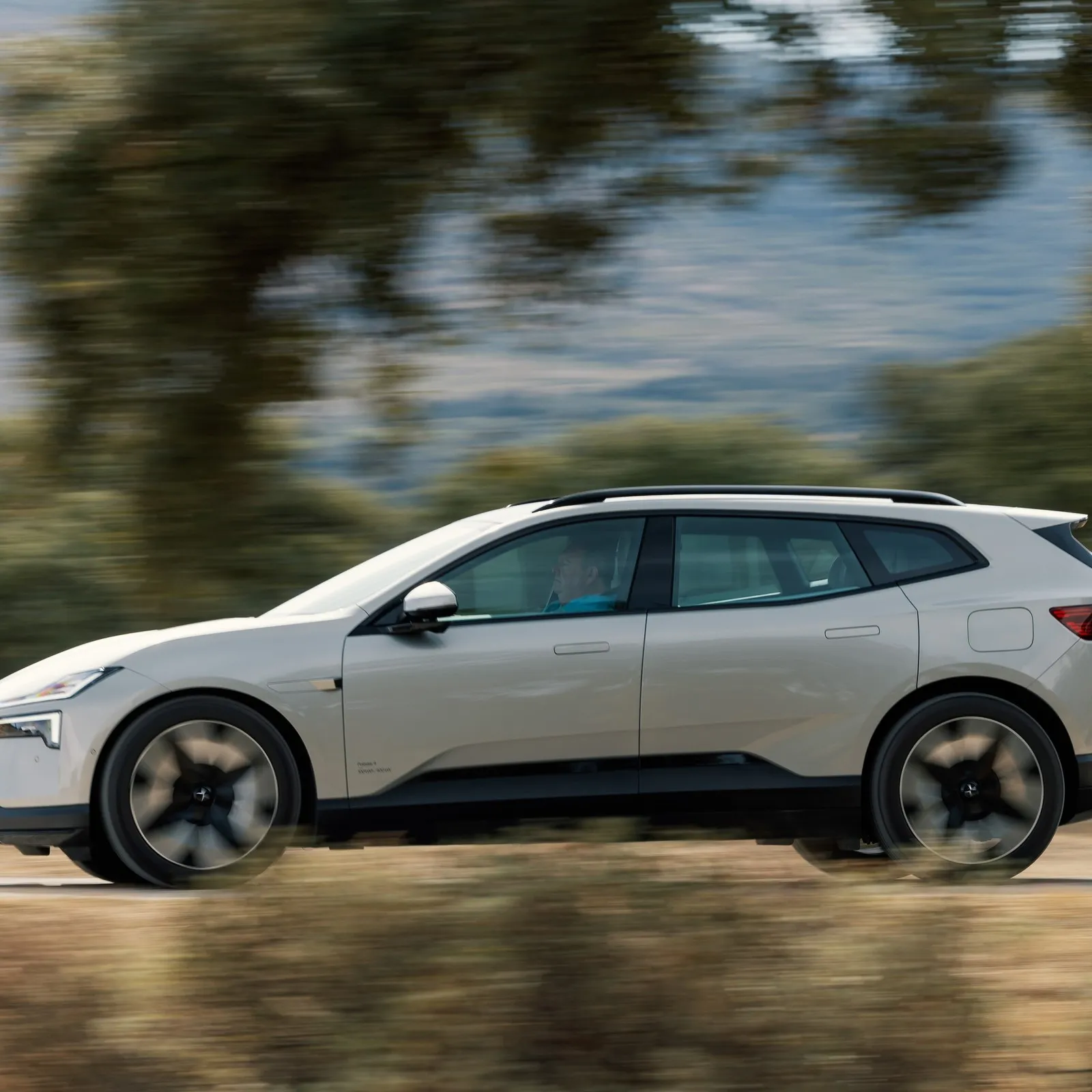Der Polestar 4 SUV beim Fahren auf einer Straße. Im Hintergrund sind Bäume verschwommen zu sehen.