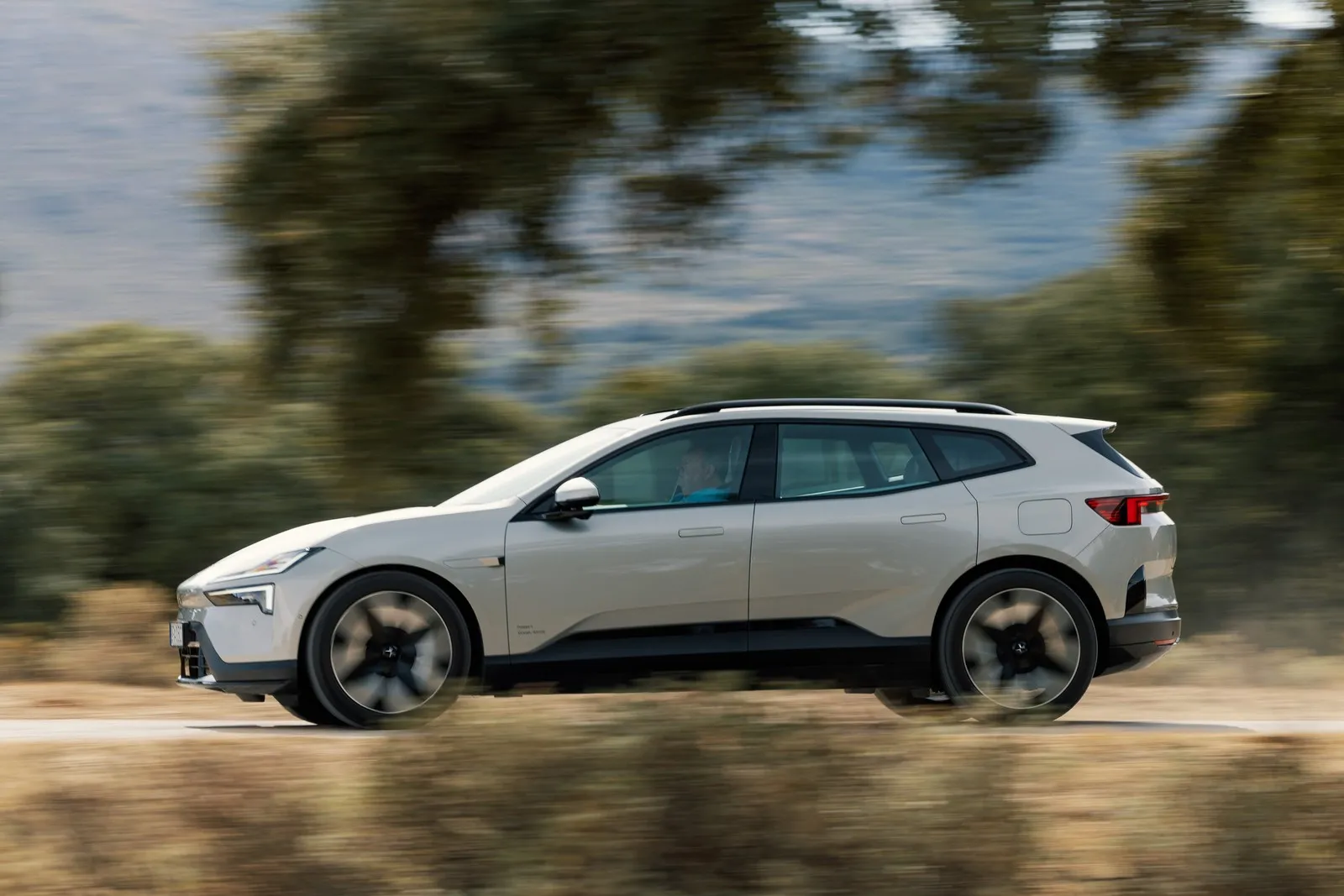 Der Polestar 4 SUV beim Fahren auf einer Straße. Im Hintergrund sind Bäume verschwommen zu sehen.