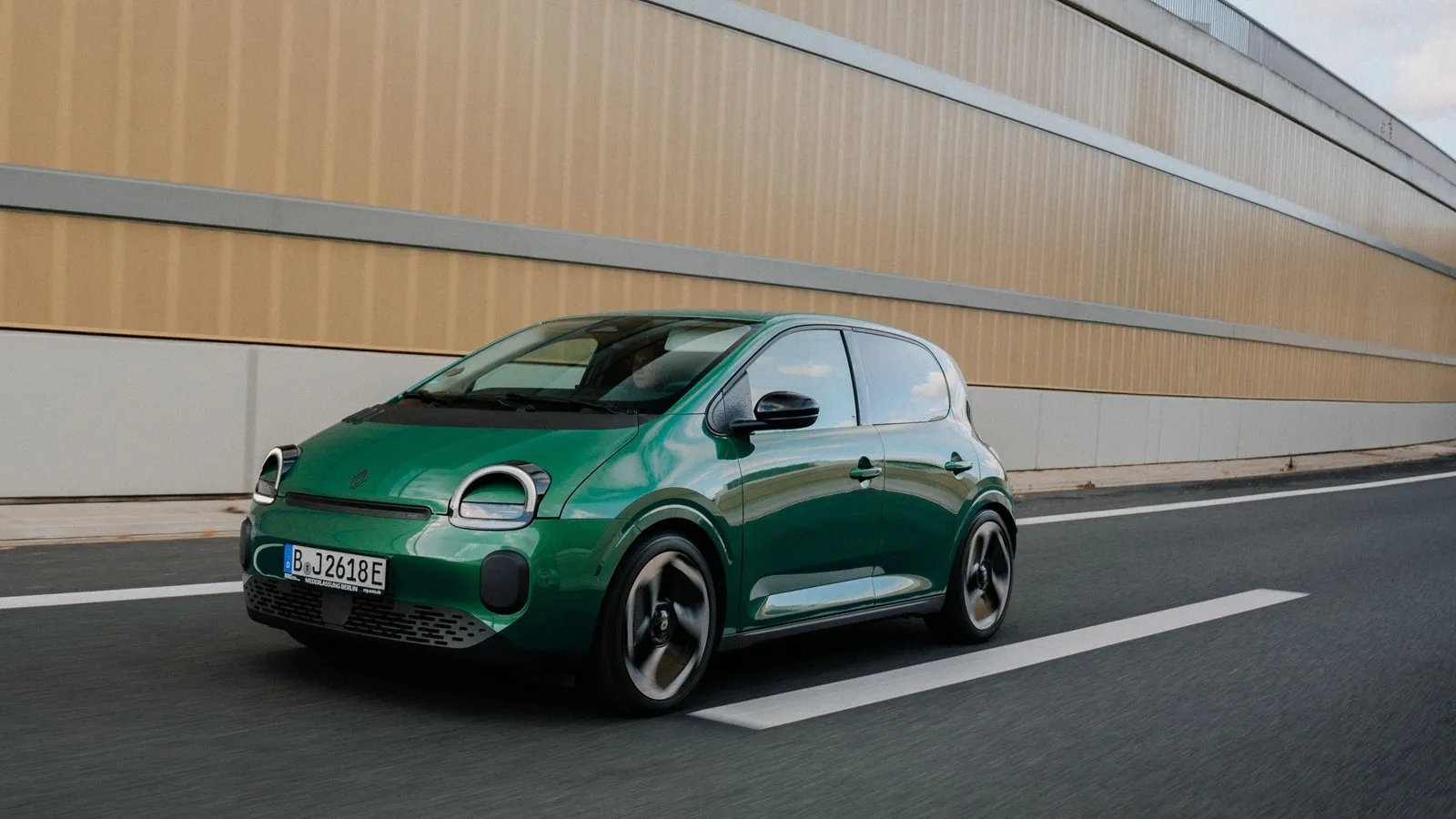 Grüner Renault Twingo Electric während der Fahrt, aufgenommen schräg von vorne.