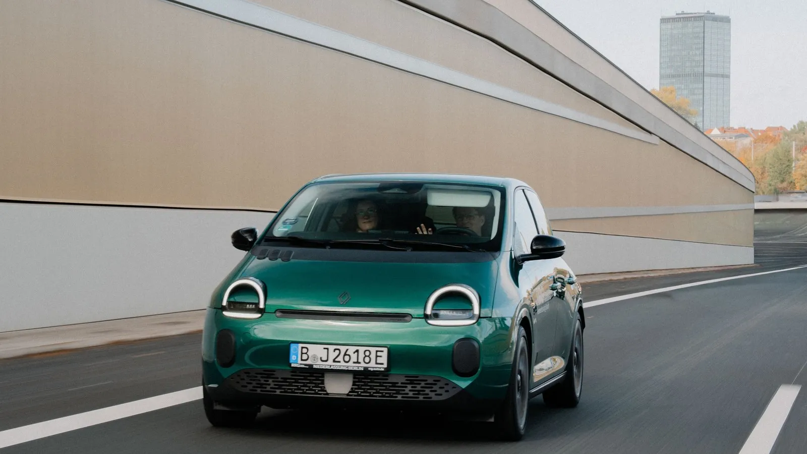 Grüner Renault Twingo Electric fährt auf einer Straße, aufgenommen aus der Frontansicht.