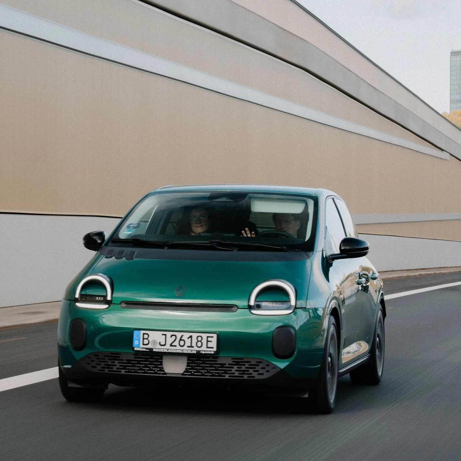 Grüner Renault Twingo Electric fährt auf einer Straße, aufgenommen aus der Frontansicht.