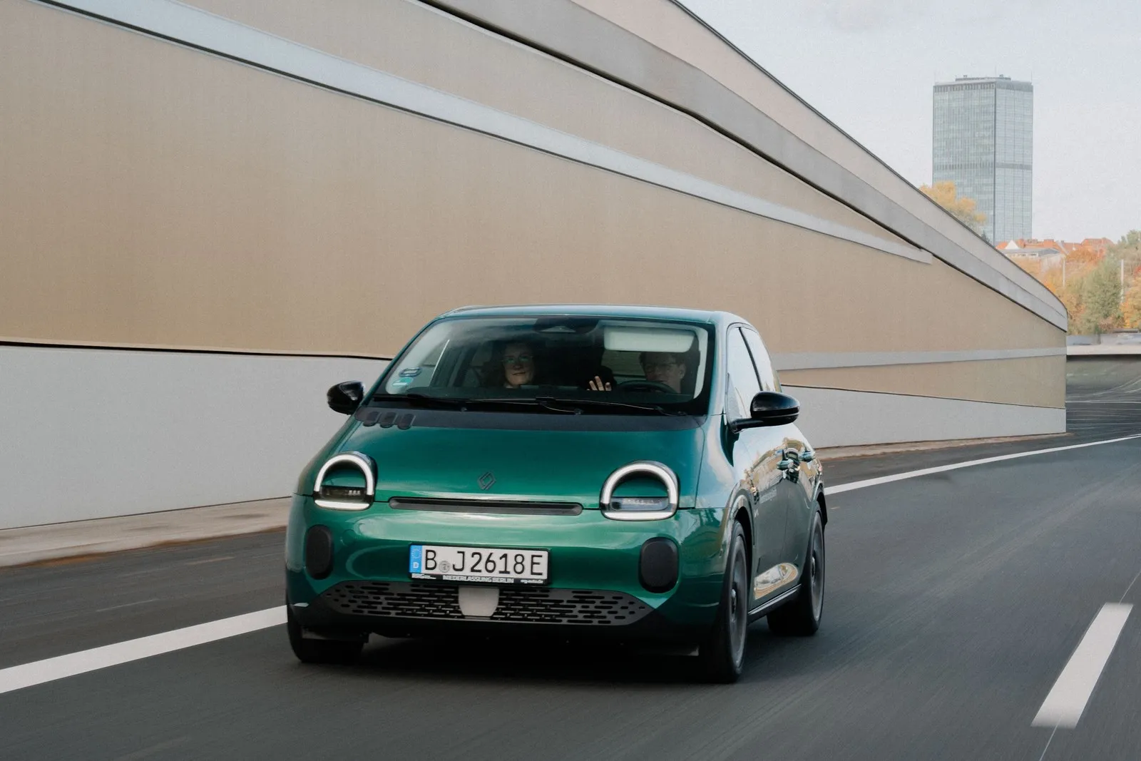 Grüner Renault Twingo Electric fährt auf einer Straße, aufgenommen aus der Frontansicht.