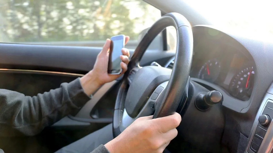 Ein Autofahrer hält am Steuer ein Handy, er benutzt es aber nicht.