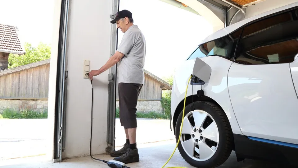Fahrer lädt Elektroauto in der Garage
